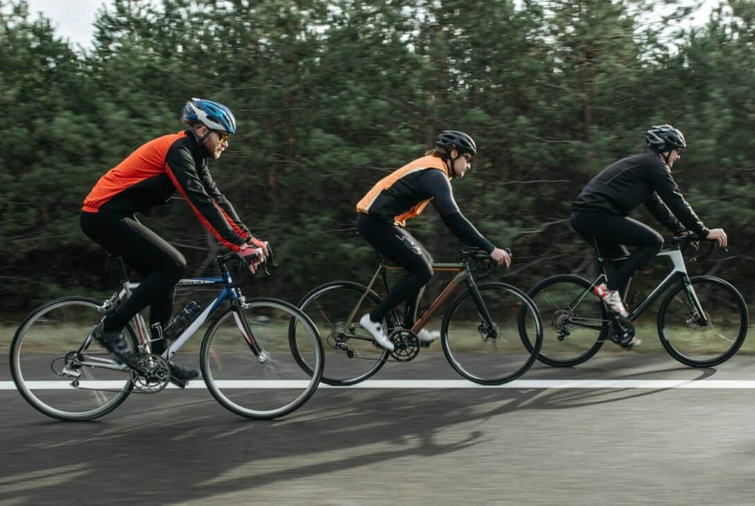 Bike riders cycling on a bike path through a forested area, emphasizing outdoor cycling and adventure.
