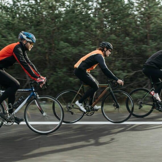 Bike riders cycling on a bike path through a forested area, emphasizing outdoor cycling and adventure.