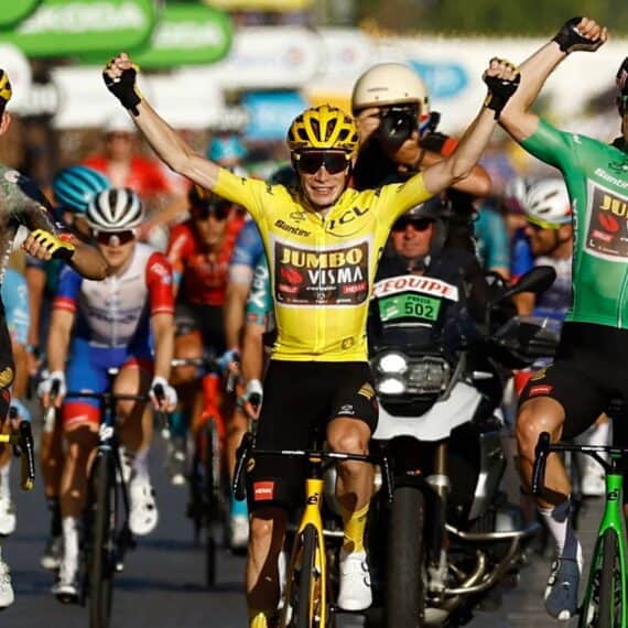 Corredores de ciclismo comemorando vitória em uma etapa de corrida de estrada, destaque para ciclistas do team Jumbo Visma e apoiadores.