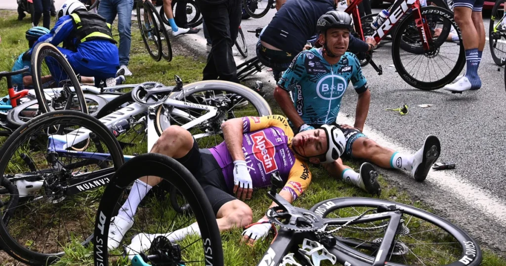 Ciclistas caidos no chão após uma queda generalizada no pelotão de ciclismo em uma competição profissional - Tour de France.