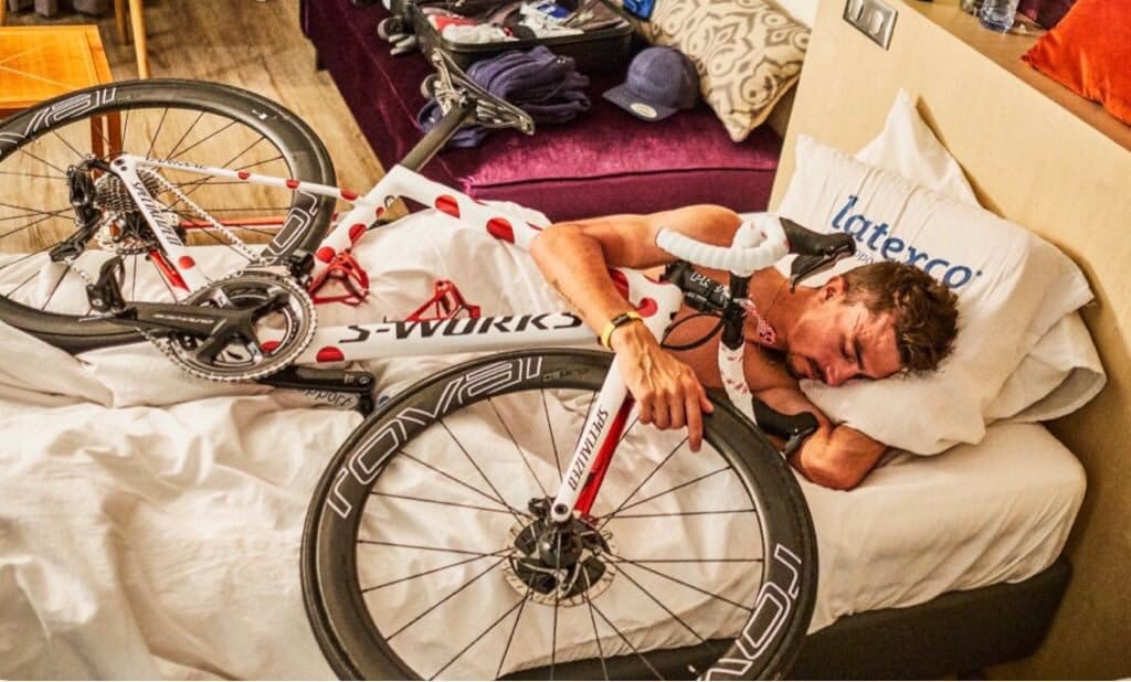 ciclista dormindo com sua bike em uma cama.