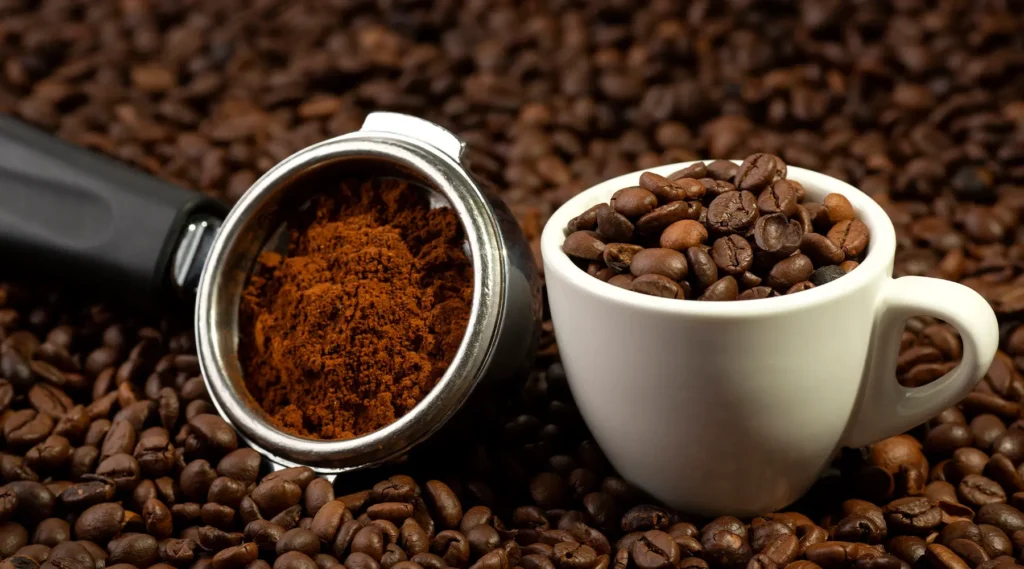 Grãos de café com uma chícara de café for cima dos Grãos.