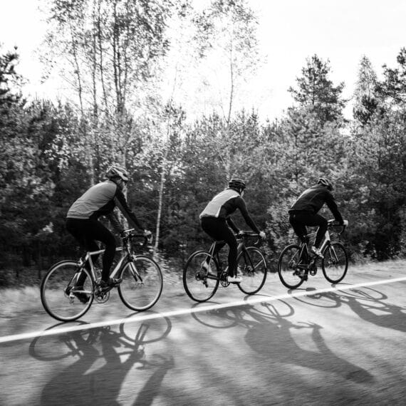 Três ciclistas treinando em uma estrada deserta.
