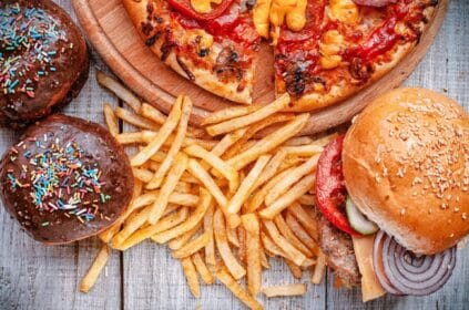 Alimentos extremamente gordurosos em cima de uma mesa: batata frita e hamburger.