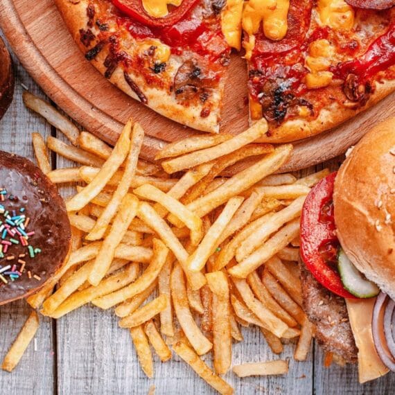 Alimentos extremamente gordurosos em cima de uma mesa: batata frita e hamburger.