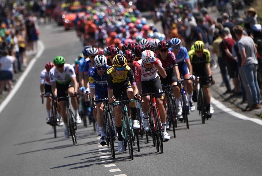 Ciclistas profissionais formando um pelotão em uma competição de ciclismo de estrada.