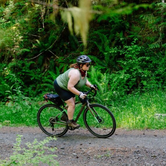 Ciclista acima do peso treinando em uma trilha na mata.