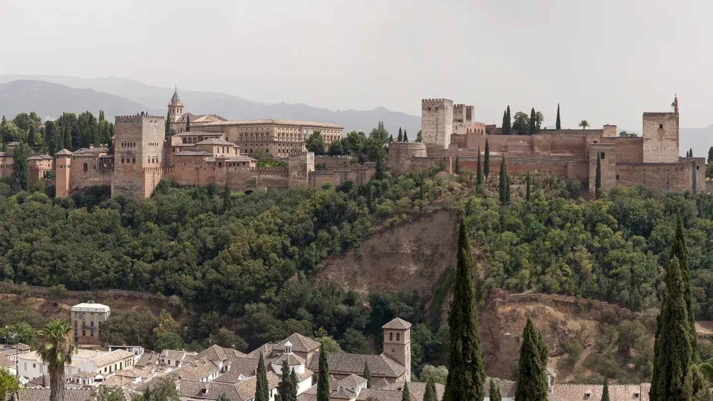 Alhambra de Granada vista do Albaicín, com as torres e muralhas sobre a colina arborizada e a cidade abaixo
