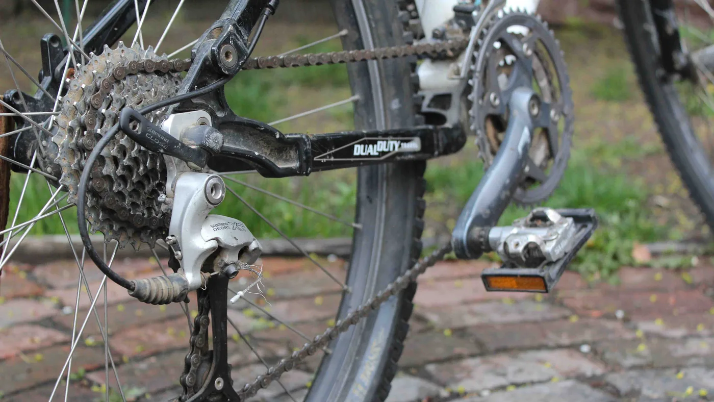 Câmbio traseiro e cassete de uma bicicleta vistos de perto, com a corrente engatada