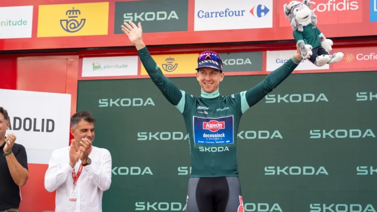 Ciclista com a camisa verde da Vuelta a España no pódio da etapa 10 de 2023, em Valladolid, de braços erguidos diante do painel do patrocinador da classificação por pontos