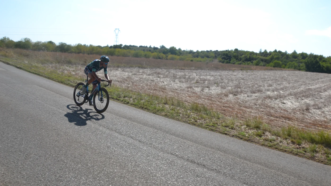 Ciclista sozinho à frente da corrida numa estrada aberta da etapa 2 da Volta a Espanha de 2026, entre campos secos do interior da França