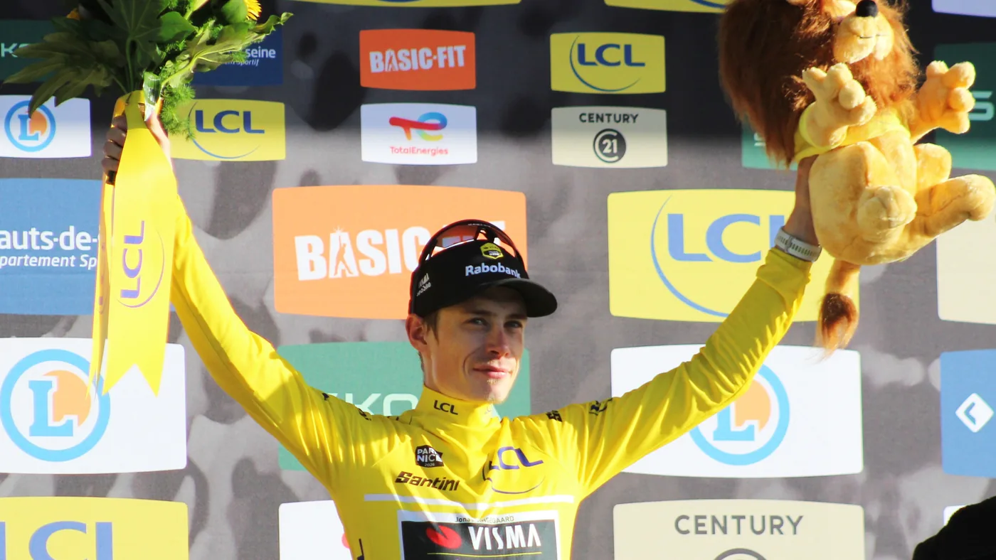 Jonas Vingegaard de amarelo ergue os braços no pódio da etapa 8 da Paris-Nice 2026, com o uniforme da Visma
