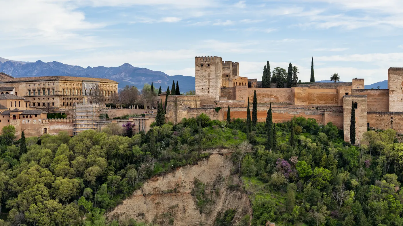 Muralhas e torres da Alhambra sobre a colina arborizada de Granada, cidade da chegada da etapa 21, às 14h07 de Brasília