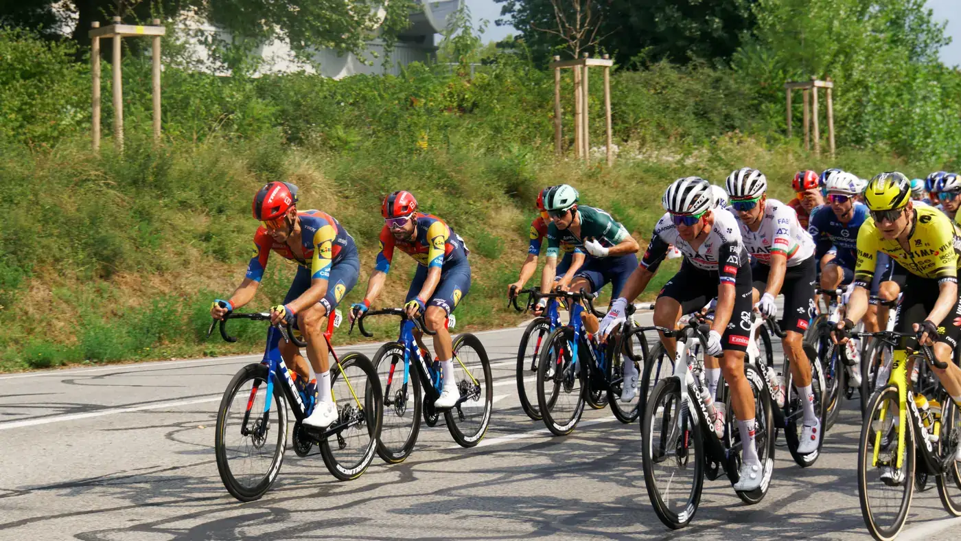 Pelotão compacto da Vuelta 2025 numa estrada de Seyssinet-Pariset, na França, durante a etapa 4