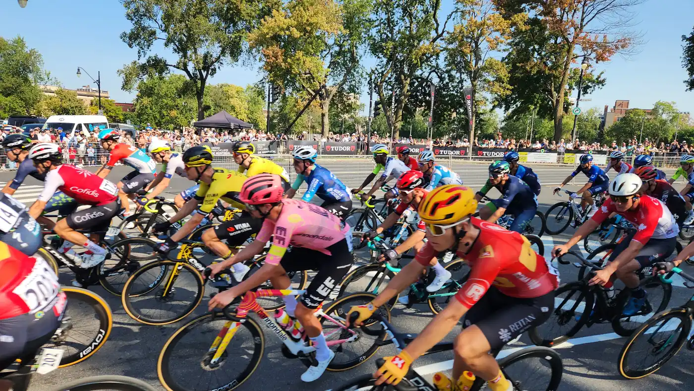 Pelotão compacto do Grande Prêmio Ciclístico de Montreal, com ciclistas de várias equipes do WorldTour lado a lado numa avenida arborizada