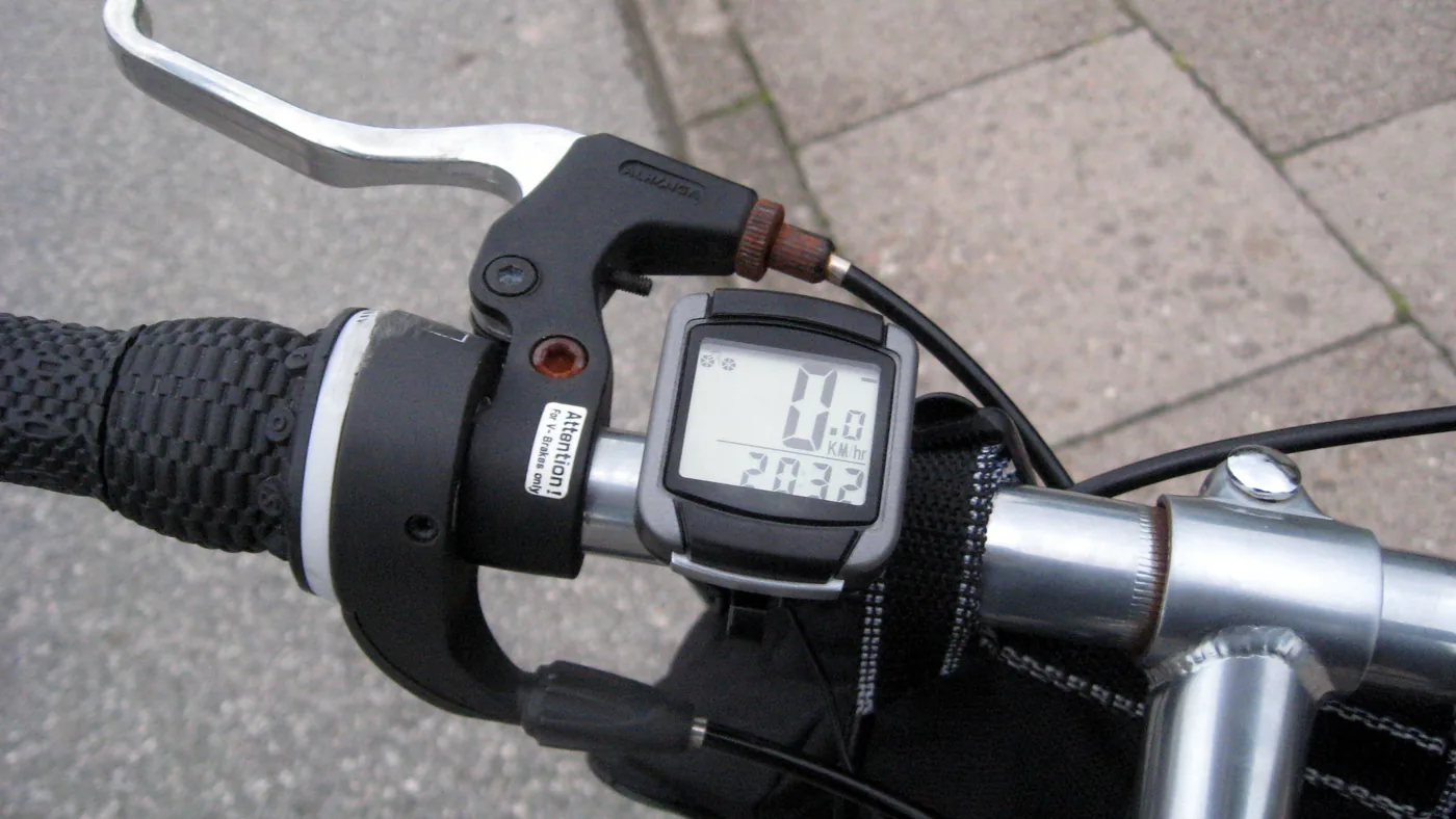 Pequeno ciclocomputador preso ao guidão ao lado do manete de freio