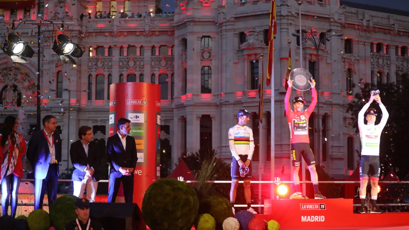 Pódio final da Vuelta 2019 em Madri: Roglič de camisa vermelha e Pogačar de camisa branca, com a Cibeles ao fundo