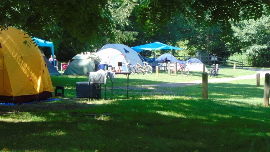 Camping com barracas montadas em gramado arborizado