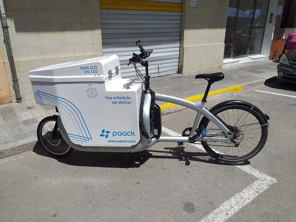 Bicicleta elétrica de carga com baú de entregas estacionada em uma rua