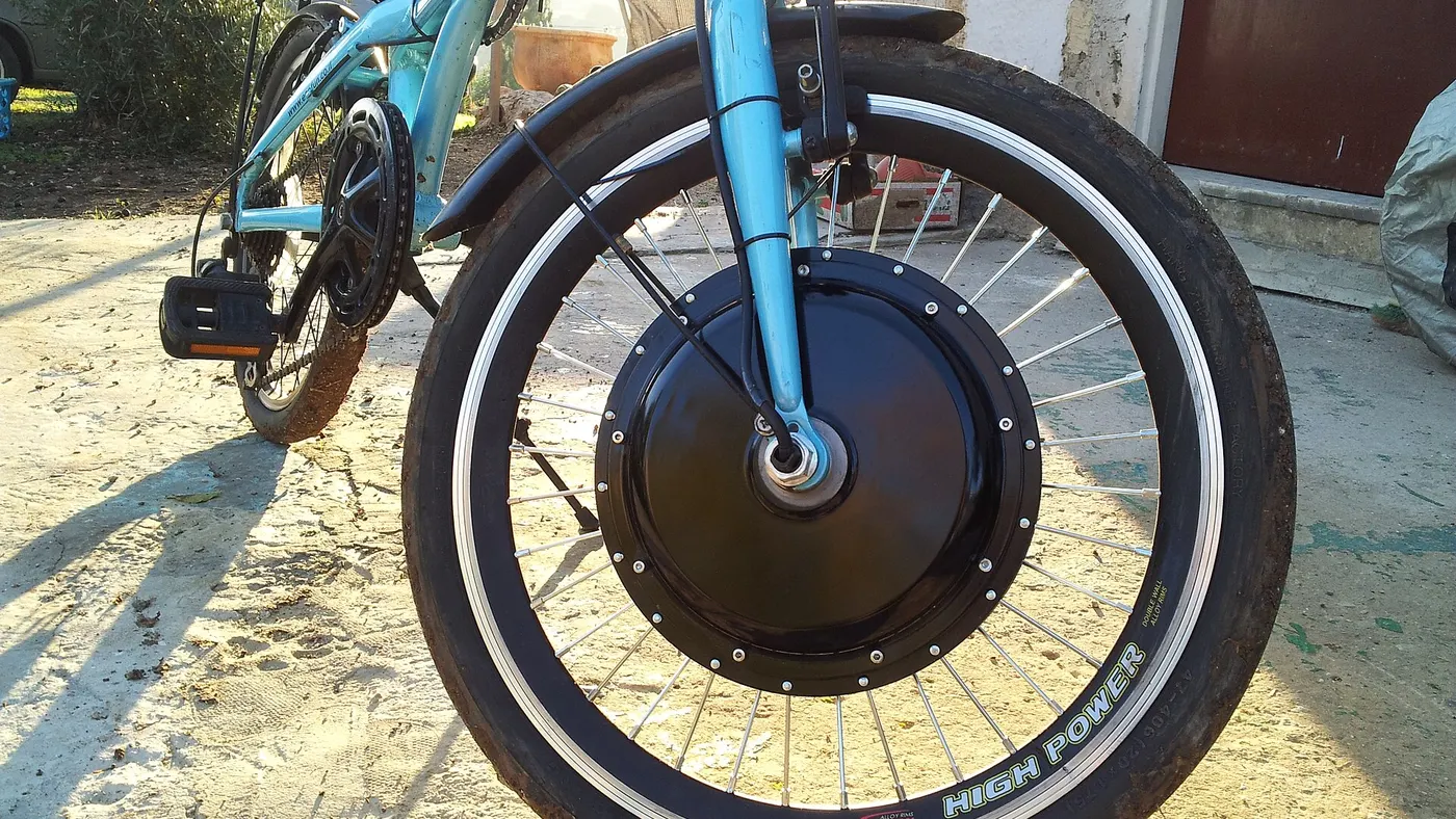 Roda dianteira com motor de cubo elétrico de grande diâmetro e aro estampado High Power, numa bicicleta dobrável adaptada